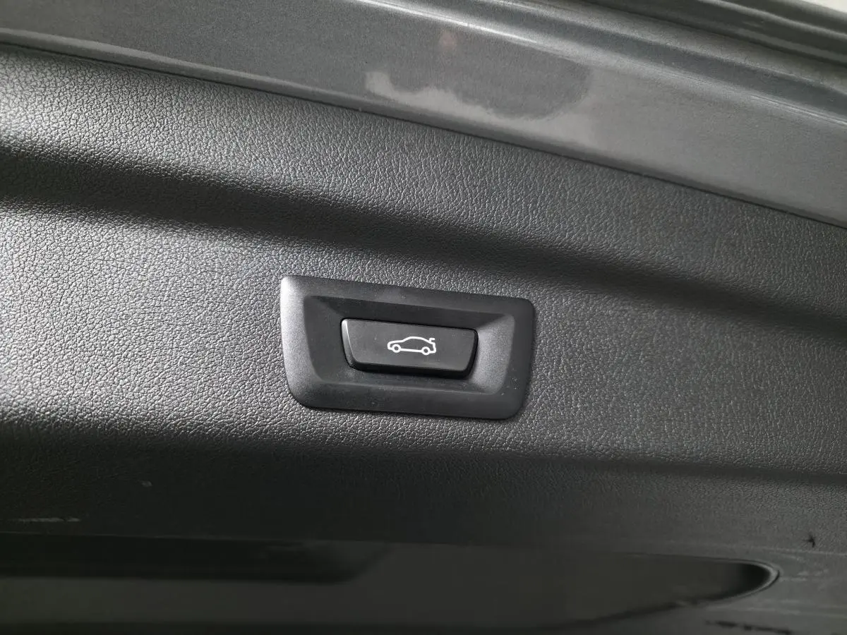 Bouton d'ouverture électrique du hayon sur la partie intérieure du coffre d'une BMW Série 2 gris métallisé.