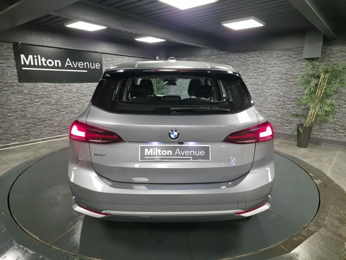 Vue arrière d'une BMW Série 2 Active Tourer gris métallisé avec feux LED allumés dans un showroom.