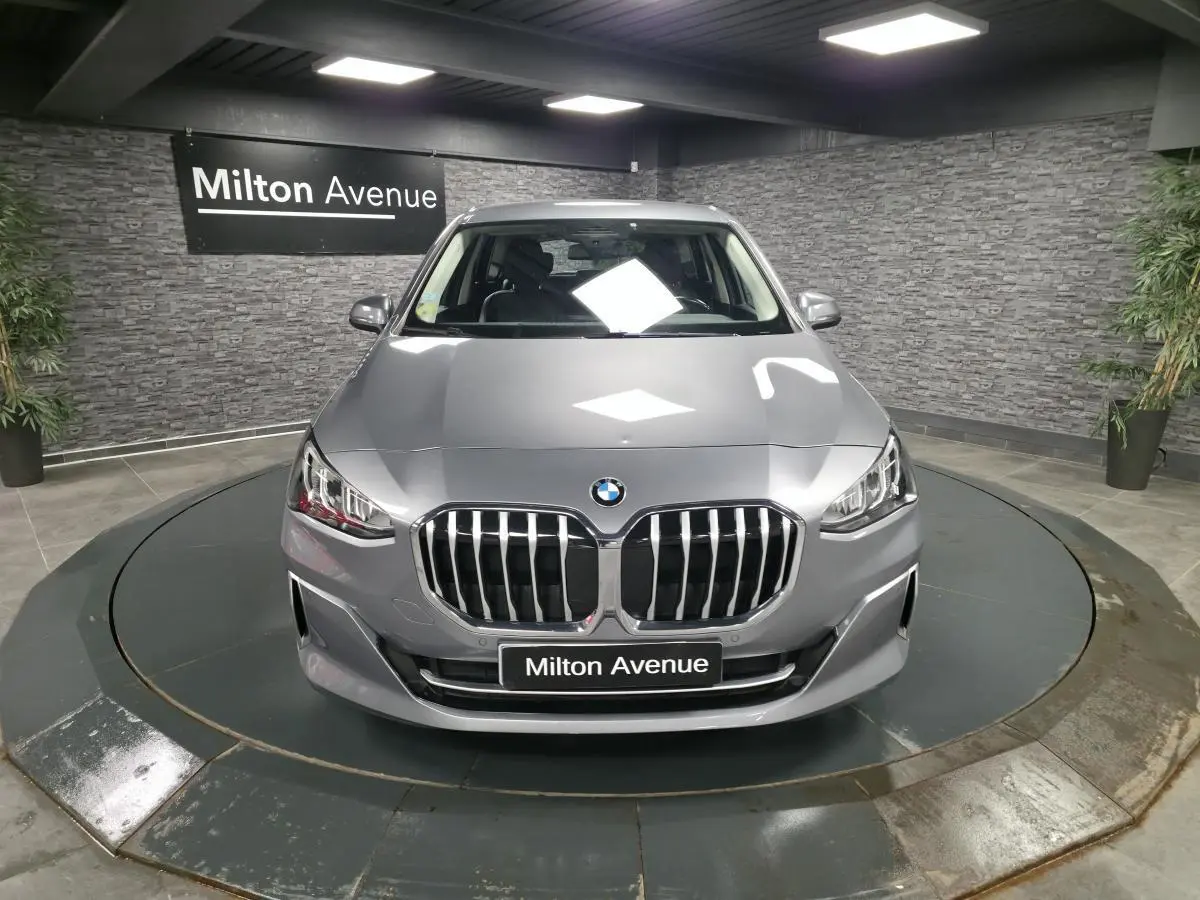 Vue avant d'une BMW Série 2 218d Active Tourer gris métallisé avec calandre chromée et phares LED en showroom.