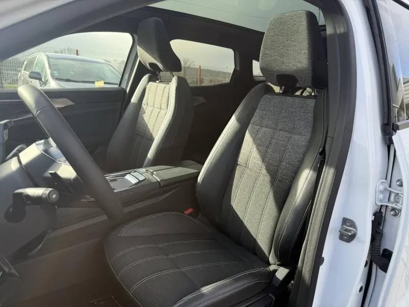 Vue intérieure côté conducteur du Renault Austral 2025 blanc nacré, sièges tissu et cuir noir avec surpiqûres blanches.