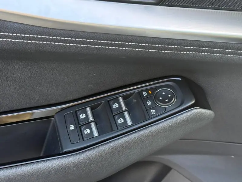 Gros plan sur la commande des vitres électriques côté gauche, garniture noire avec surpiqûres blanches, Renault Austral 2025.