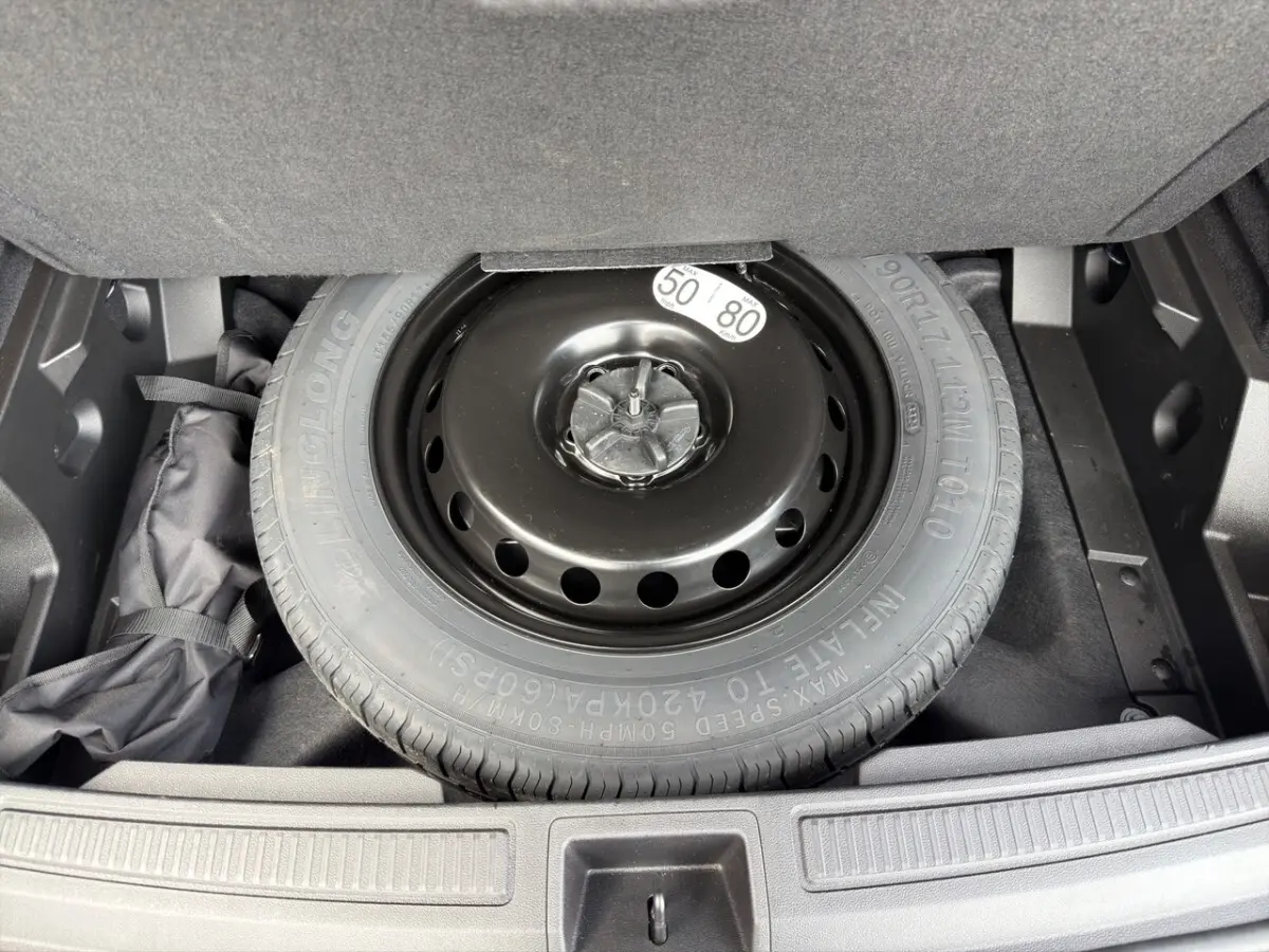 Vue plongeante sur la roue de secours noire dans le coffre du Renault Austral gris foncé 2025.