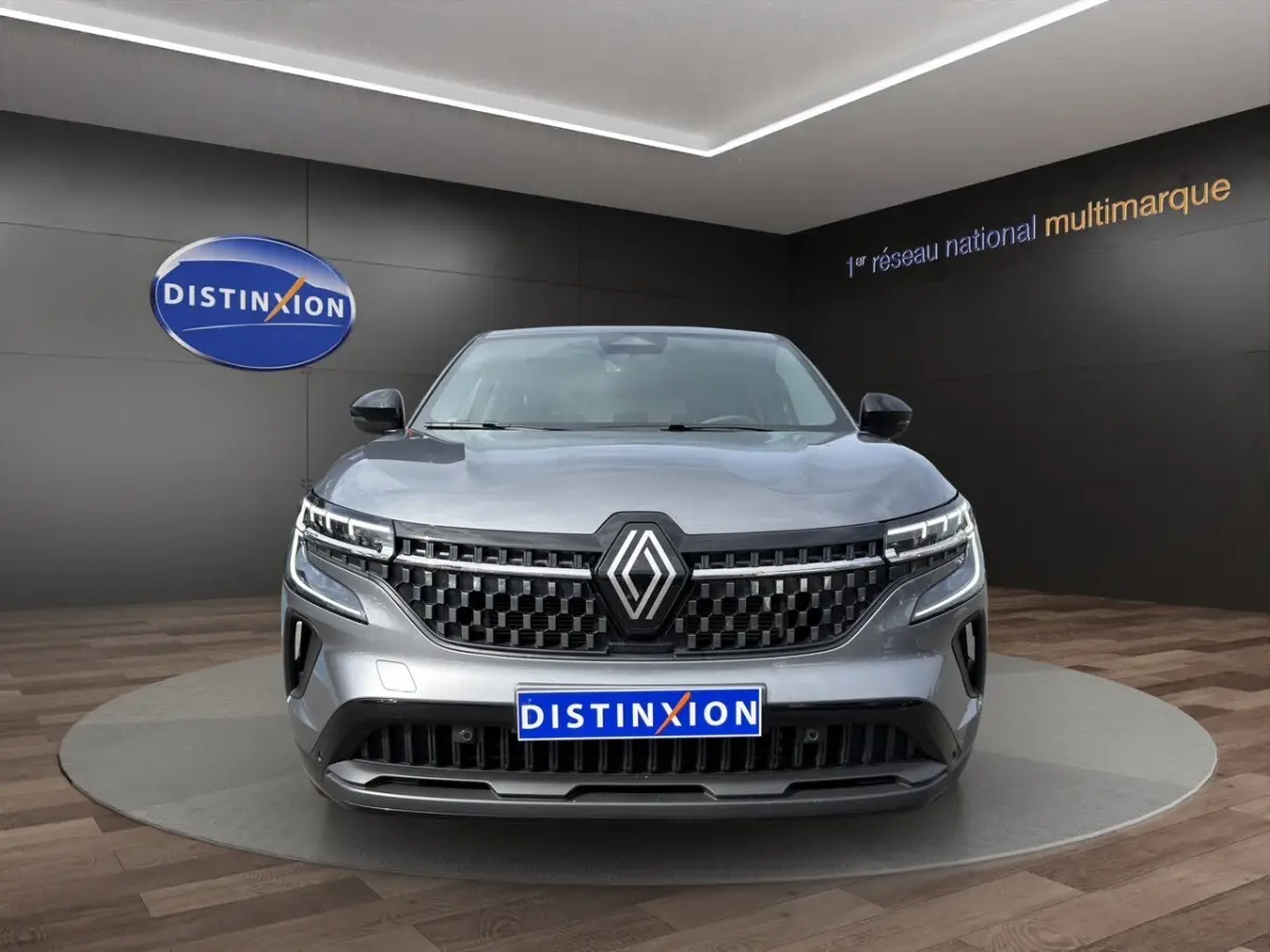 Vue frontale d’un Renault Austral gris foncé avec calandre noire et feux LED distinctifs en showroom.