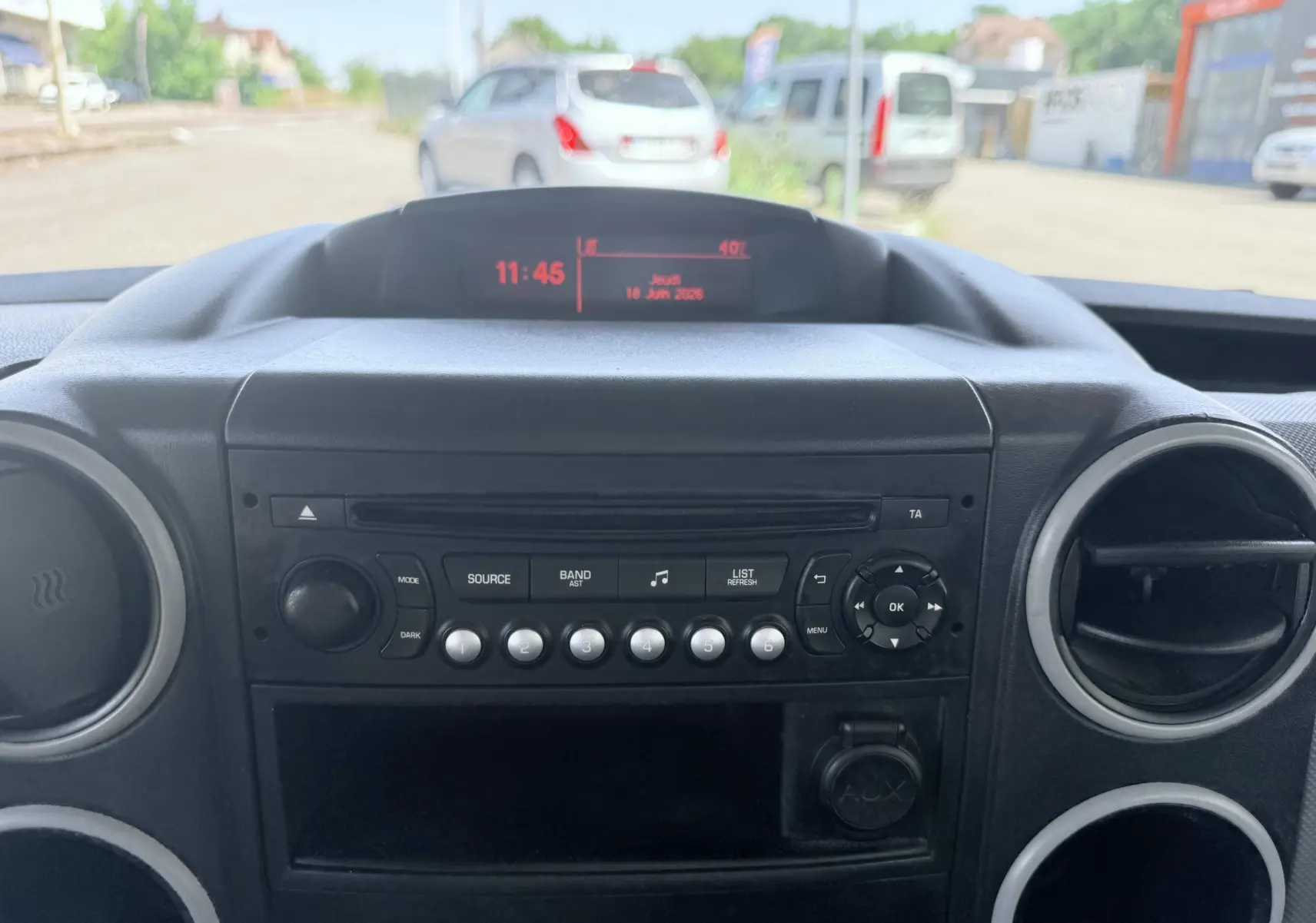 Vue intérieure du tableau de bord du Peugeot Partner blanc 2014, mettant en valeur la console centrale et l’écran digital.