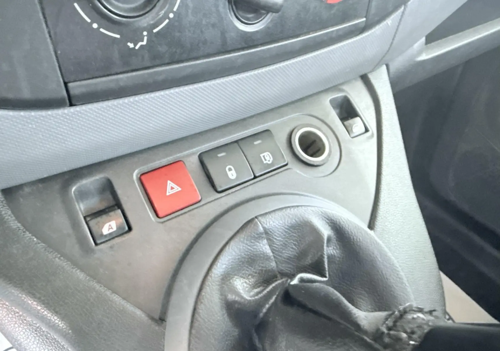 Gros plan sur la console centrale du Peugeot Partner blanc 2014, montrant la commande de boîte manuelle et les boutons de sécurité.