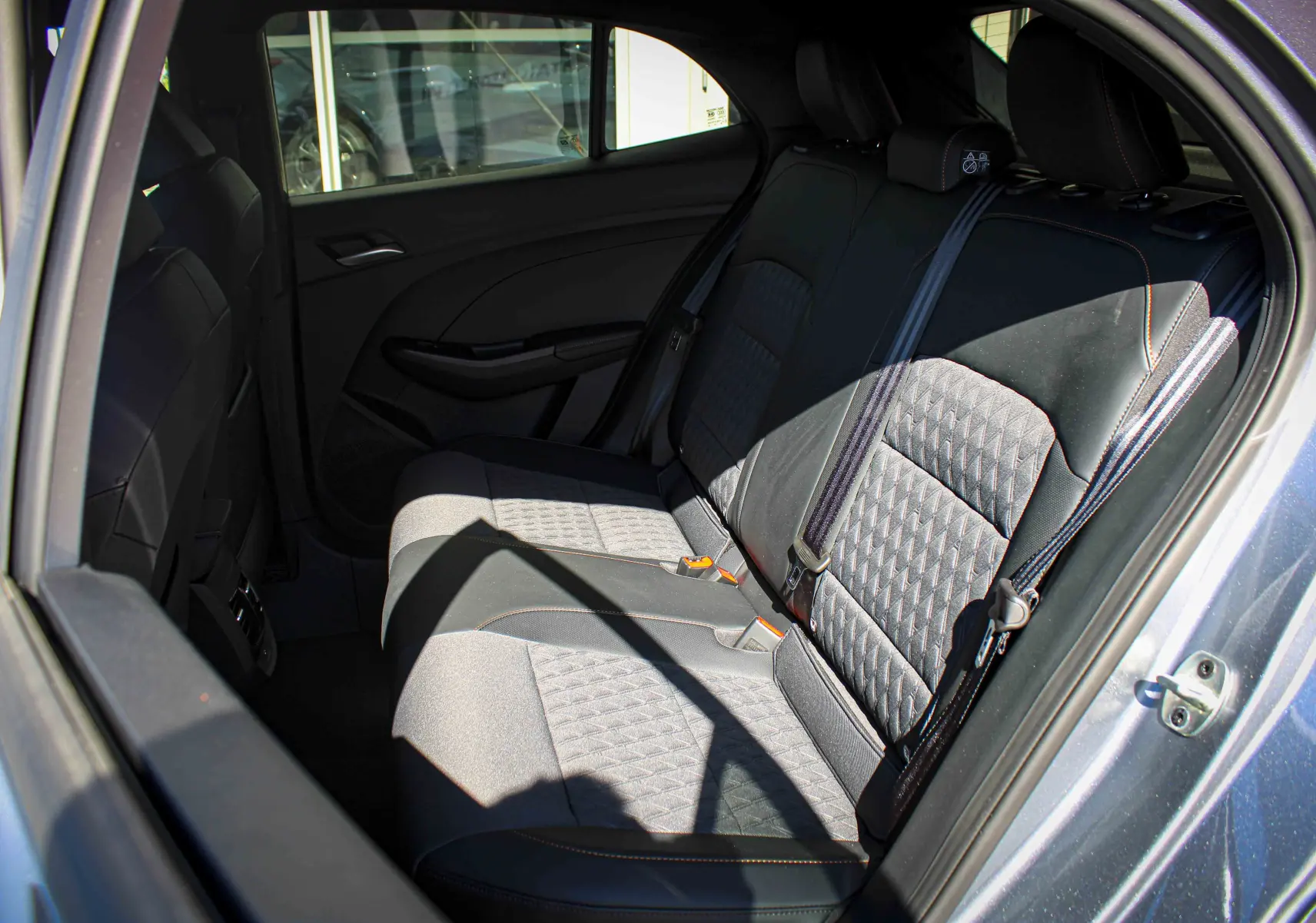 Vue intérieure côté droit des sièges arrière en tissu noir avec surpiqûres orange d'une MG3 1.5L HYBRID+ 195CH LUXURY gris métallisé.