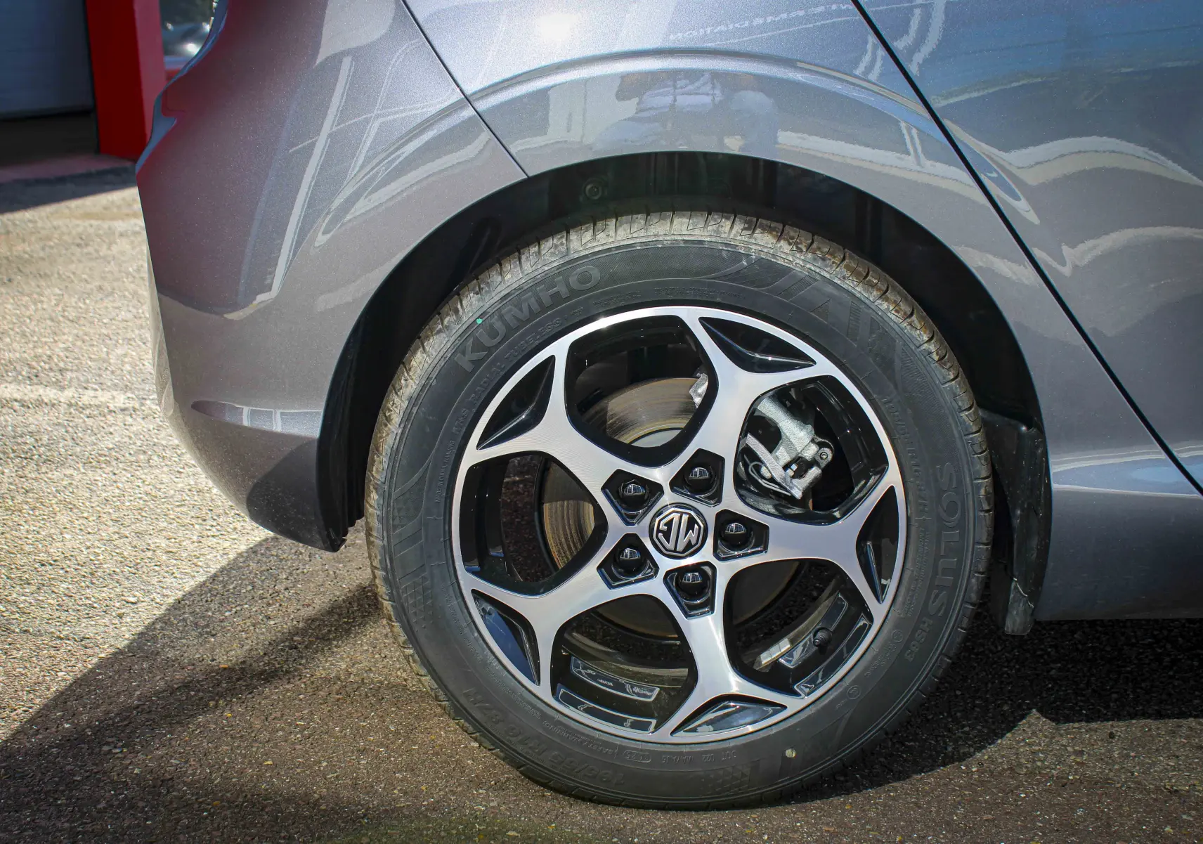 Gros plan sur la roue arrière droite grise métallisée d'une MG3 1.5L Hybrid+ 195ch Luxury avec jante alliage noire et argent.