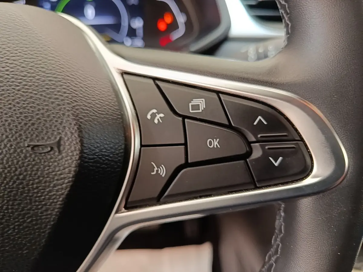 Gros plan sur les commandes multifonctions du volant cuir synthétique du Renault Captur Business E-Tech hybride gris clair.