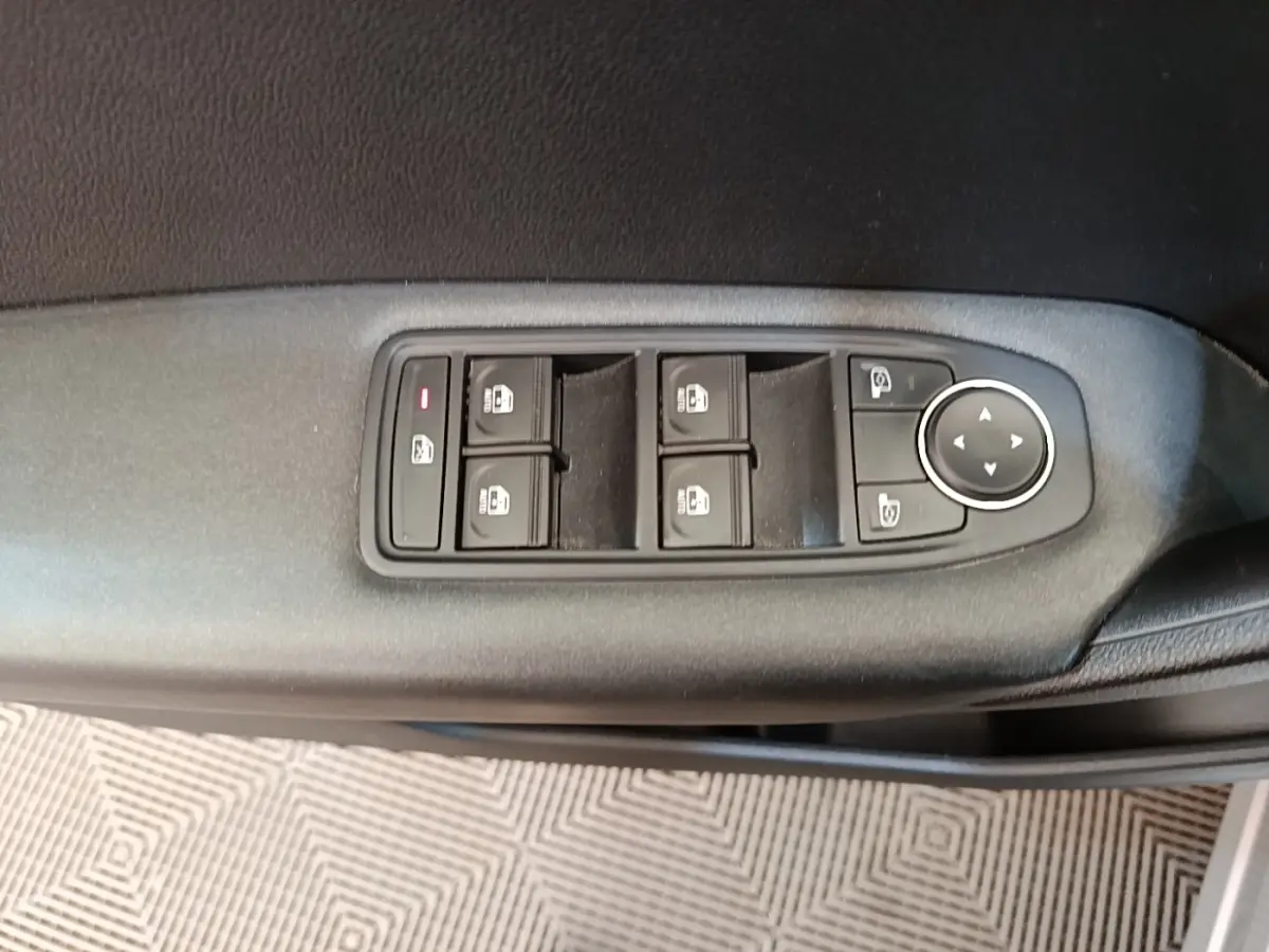 Gros plan sur les commandes de lève-vitres et rétroviseurs sur la porte côté conducteur d’un Renault Captur Business E-Tech hybride.