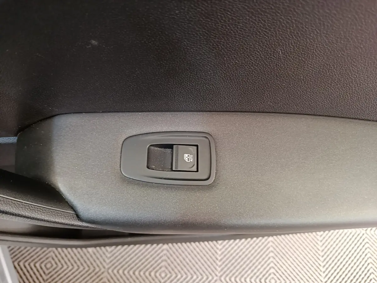Gros plan sur le bouton de commande de la vitre électrique côté conducteur du Renault Captur Business E-Tech gris clair.
