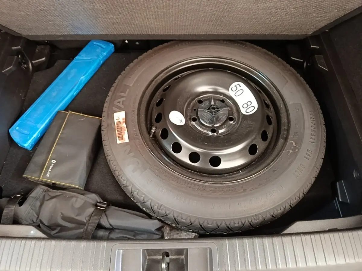 Vue plongeante sur la roue de secours noire et les accessoires dans le coffre du Renault Captur gris clair 2022.