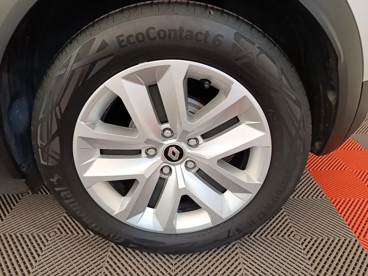 Gros plan sur la jante alliage argentée avec logo Renault au centre du Renault Captur gris clair.