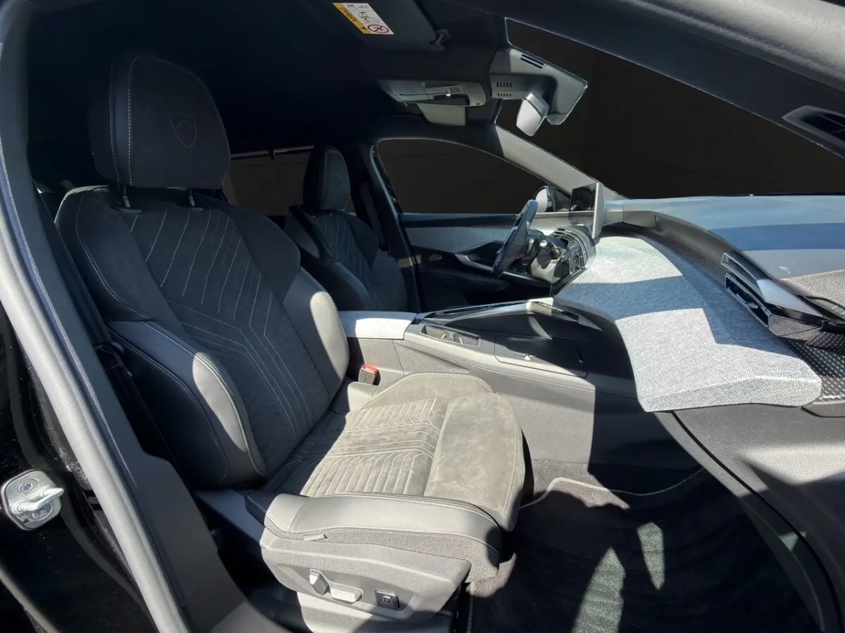 Vue intérieure côté conducteur du Peugeot 5008 noir 2025, sièges Alcantara et tableau de bord moderne avec écran tactile.