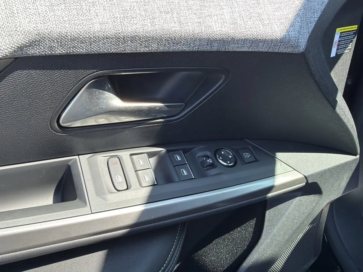 Gros plan sur la porte intérieure côté conducteur du Peugeot 5008 noir, montrant les commandes des vitres et rétroviseurs.