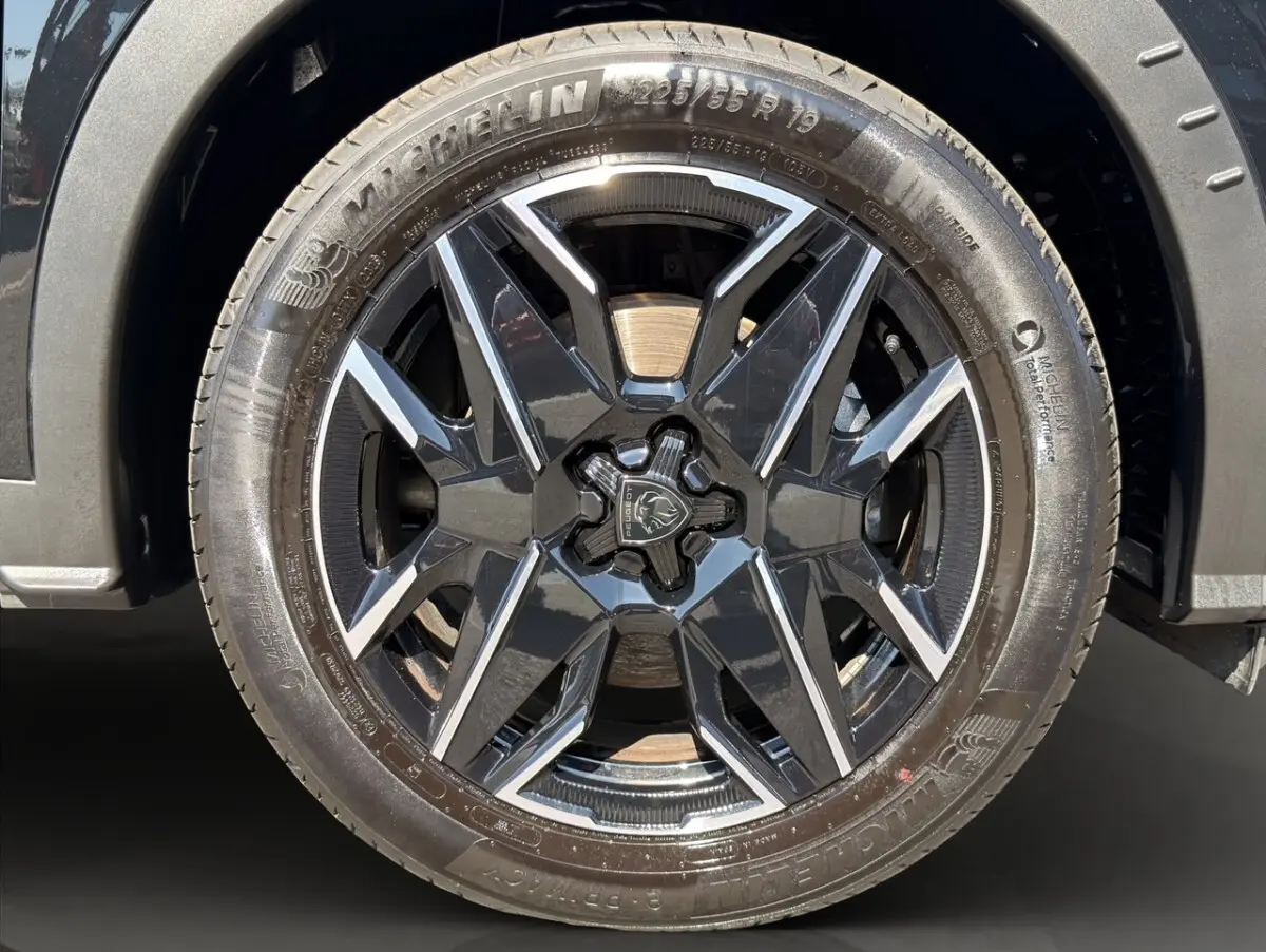 Gros plan sur la roue avant droite noire du Peugeot 5008 1.2 Hybrid 145 GT avec jante alliage noire et argentée.