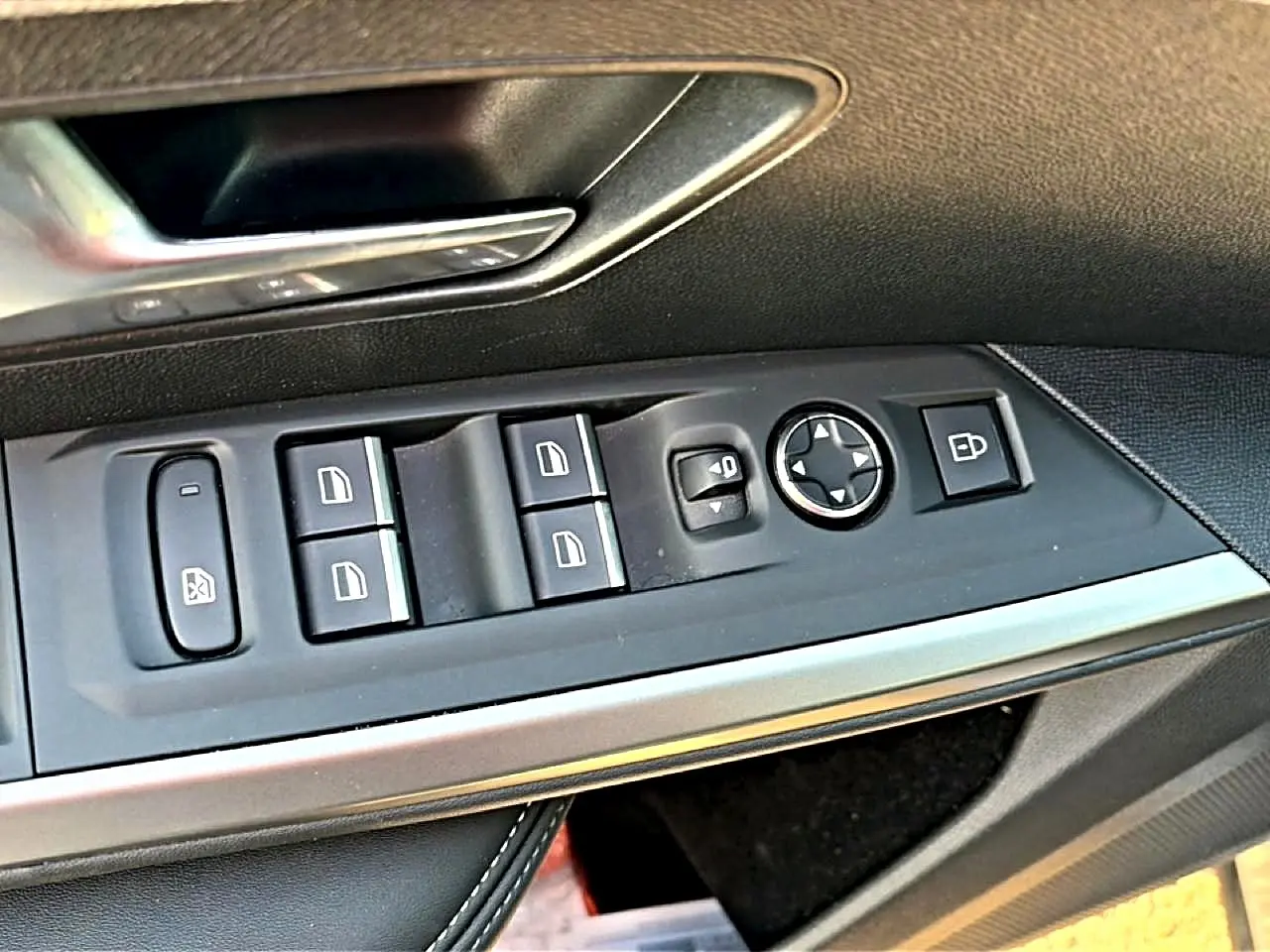 Vue rapprochée des commandes de lève-vitres et rétroviseurs sur la porte côté conducteur d’un Peugeot 3008 gris.