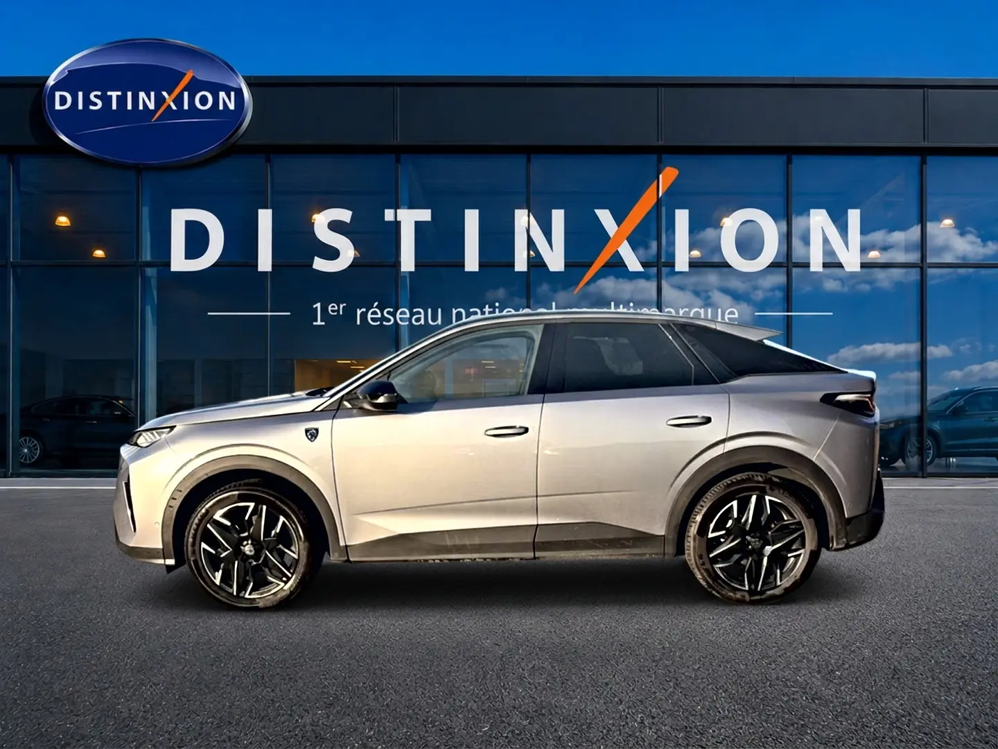 Profil droit du Peugeot 3008 gris 2025 devant une vitrine avec logo Distinxion, jantes alliage visibles.