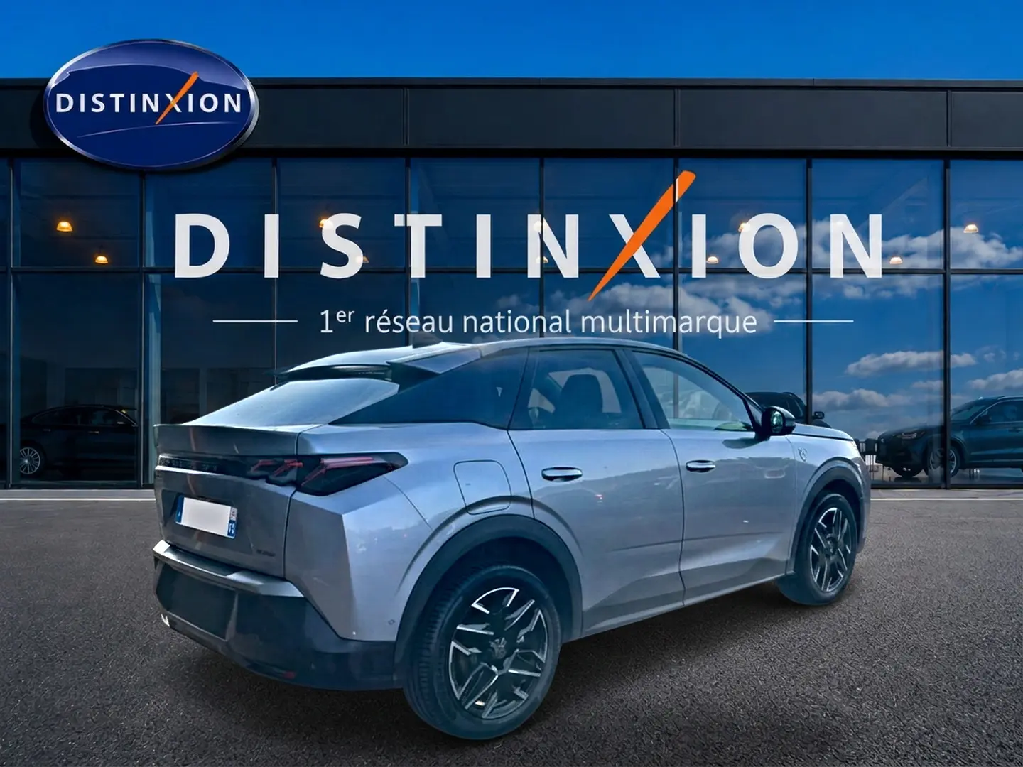 Peugeot 3008 gris 3/4 arrière droit, avec jantes alu noires et feux arrière LED distinctifs, devant vitrine Distinxion.