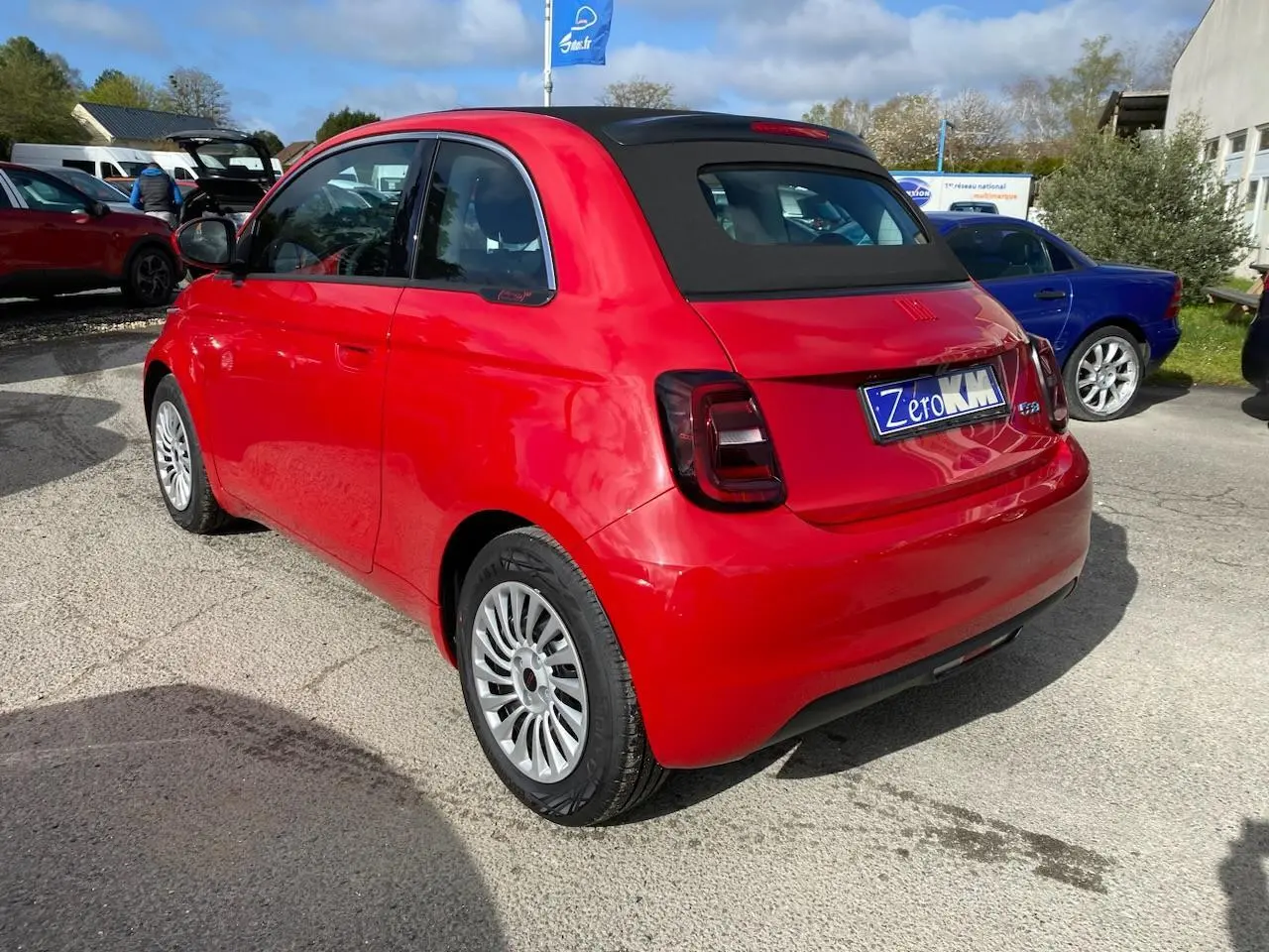 Vue 3/4 arrière droite d'une FIAT 500 Cabriolet électrique rouge avec toit noir et jantes alliage 16 pouces.
