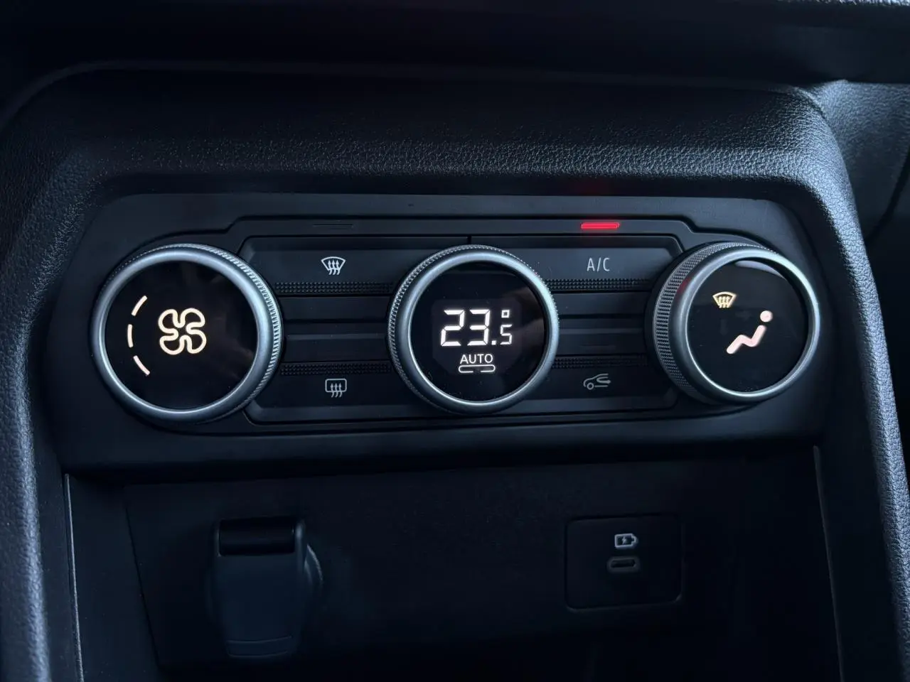 Gros plan sur les commandes de climatisation automatique du Dacia Jogger Gris Schiste, affichant 23,5°C.