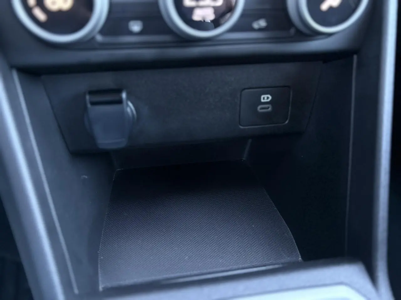 Gros plan sur la console centrale noire du Dacia Jogger 2025, montrant une prise USB-C et un espace de rangement.