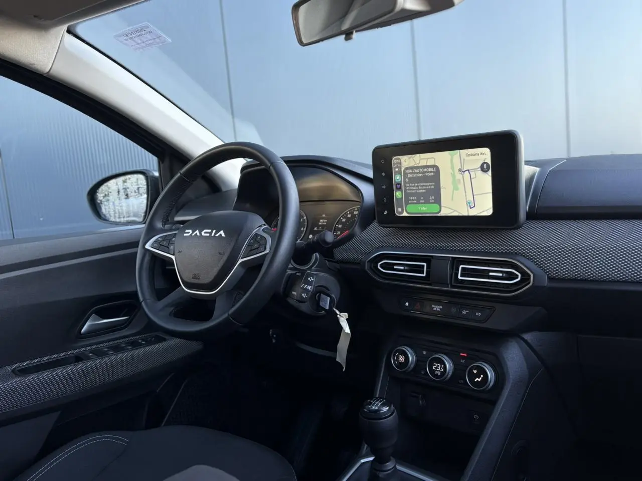 Vue intérieure côté conducteur du tableau de bord du Dacia Jogger gris avec écran tactile GPS et volant multifonctions.