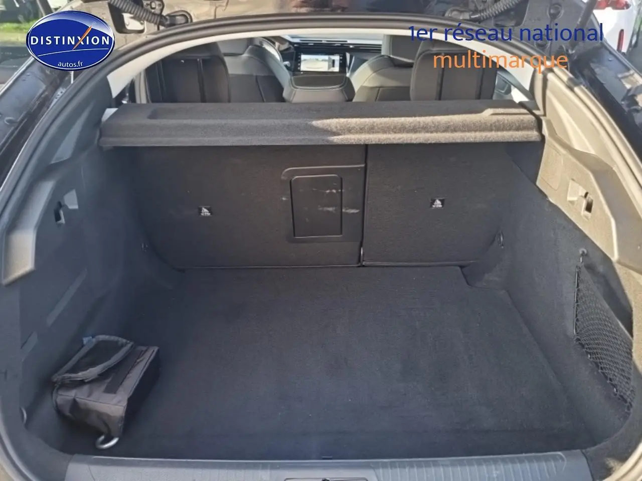 Vue intérieure du coffre noir ouvert du Peugeot 408 Hybrid 145 allure e-dcs6, avec banquette arrière et cache-bagages visibles.
