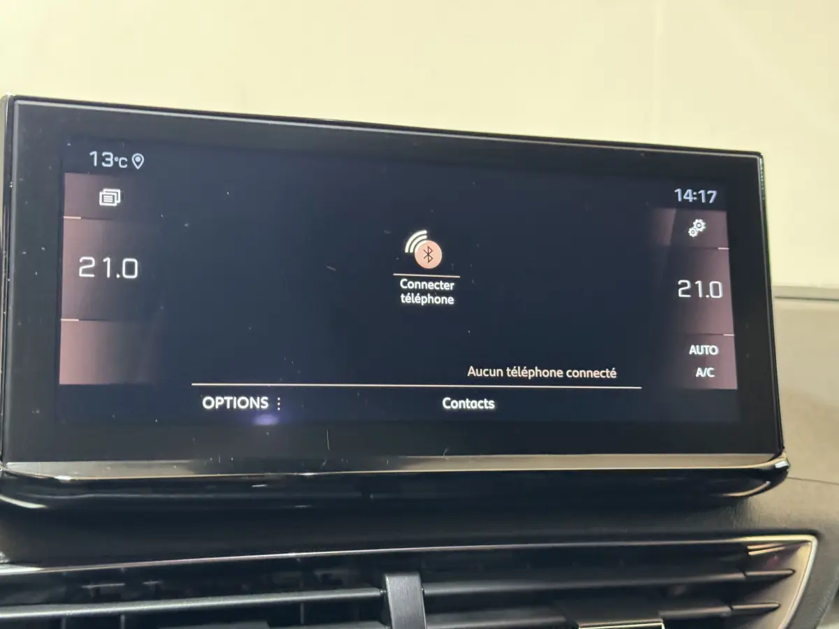 Écran tactile central affichant la connexion Bluetooth et la température à 21°C dans un Peugeot 3008 gris clair, vue intérieure frontale.