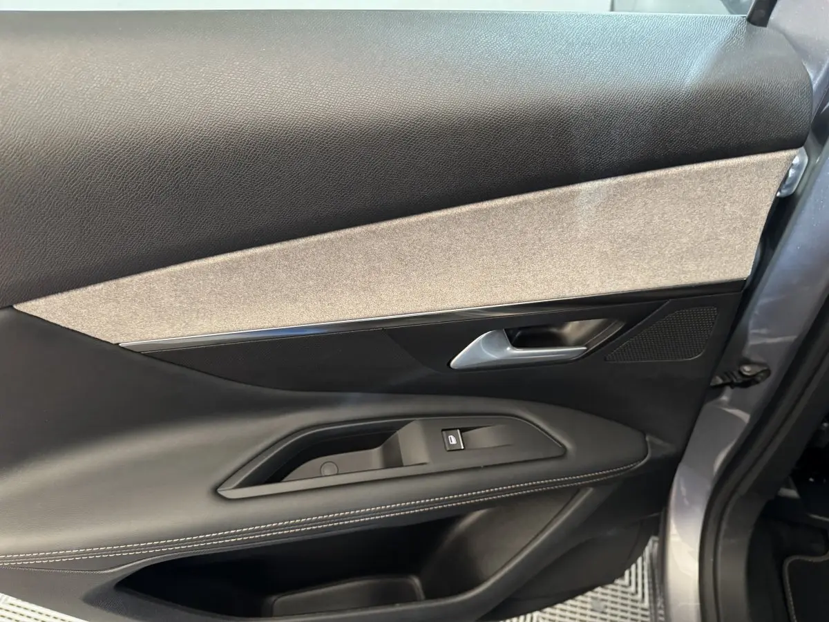 Vue rapprochée de la porte avant droite gris clair du Peugeot 3008 2021 avec garniture noire et beige et commande de vitre.
