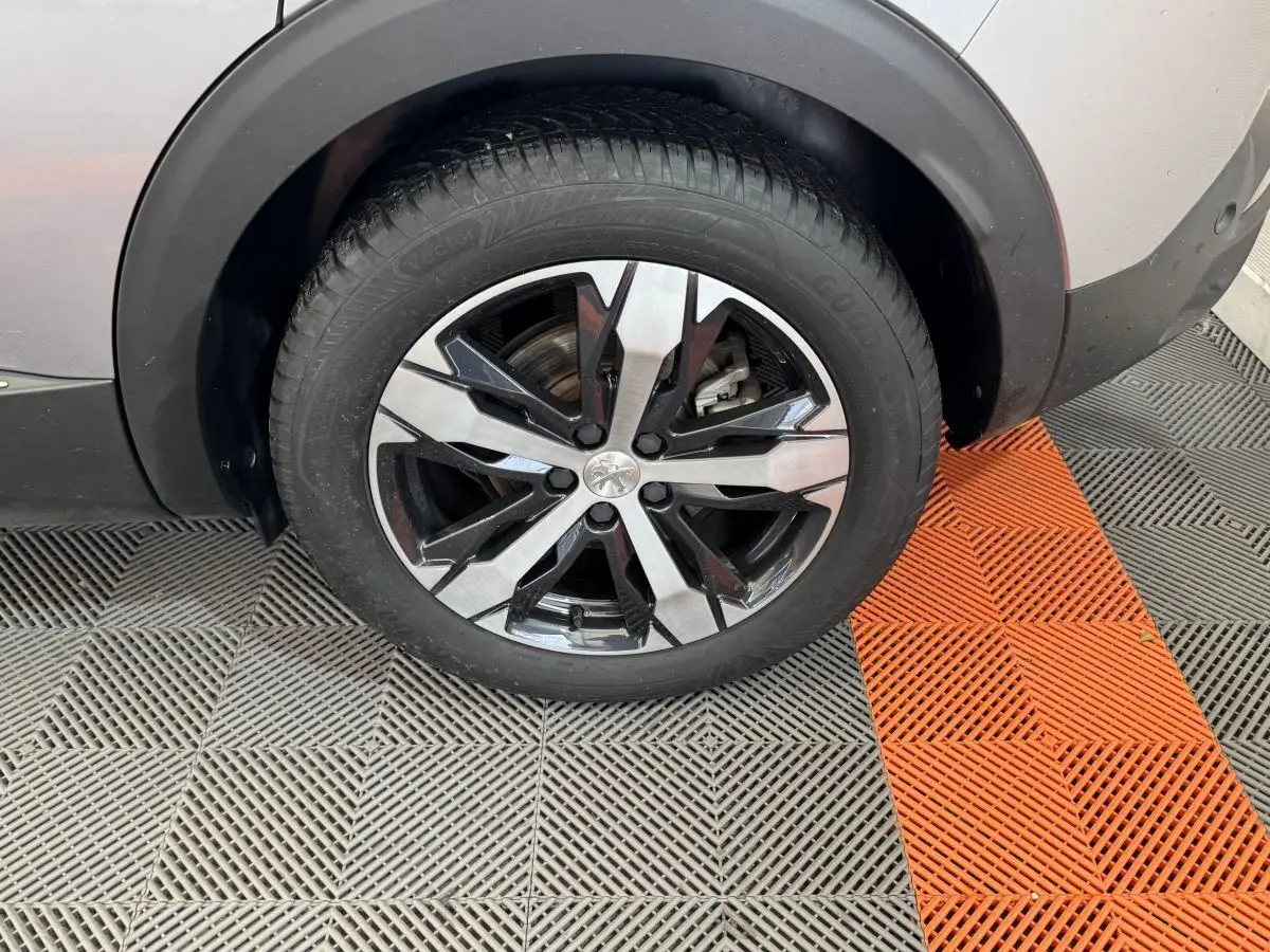 Gros plan sur la roue avant droite gris clair du Peugeot 3008 avec jante alliage bicolore moderne.
