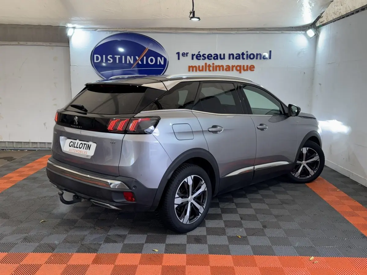 Vue 3/4 arrière droite d’un Peugeot 3008 GT gris clair avec toit noir et feux arrière LED distinctifs.