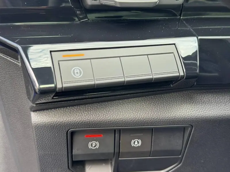Gros plan sur les commandes intérieures noires du Renault Austral 2025, avec bouton de verrouillage et frein à main électronique.