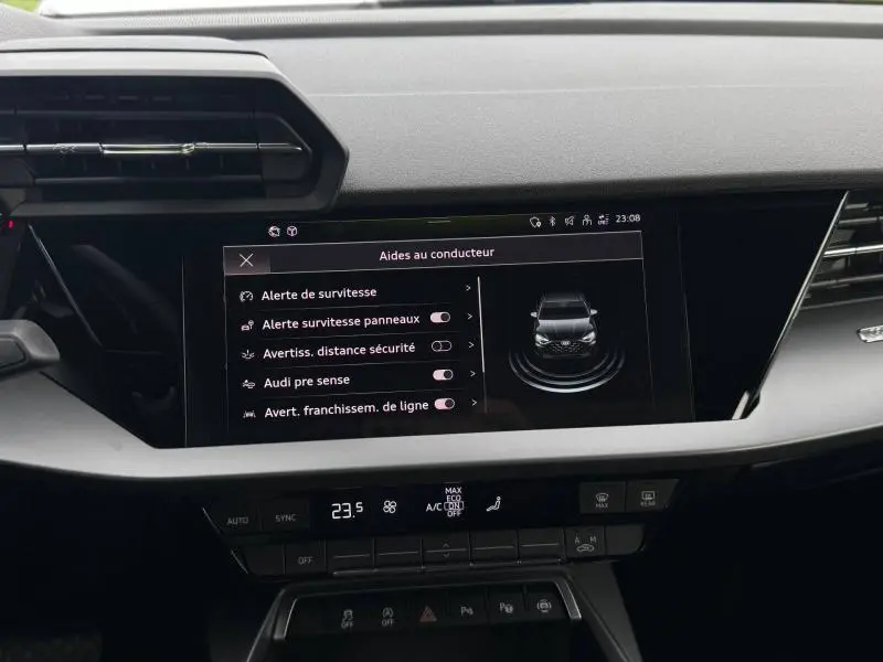 Vue rapprochée de l’écran tactile central de l’Audi A3 Sportback 2024 affichant les aides à la conduite, intérieur noir.
