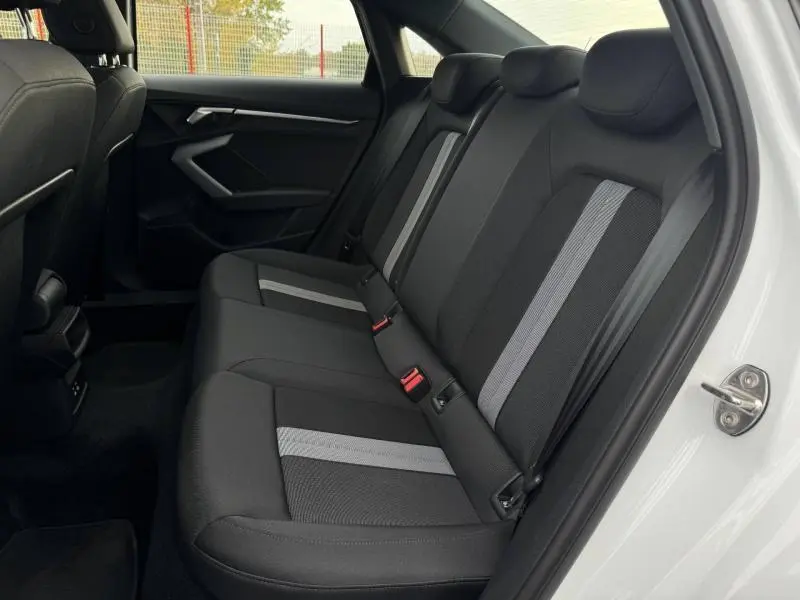 Vue intérieure arrière côté droit de la banquette tissu noir avec bandes grises dans une Audi A3 Sportback blanche 2024.