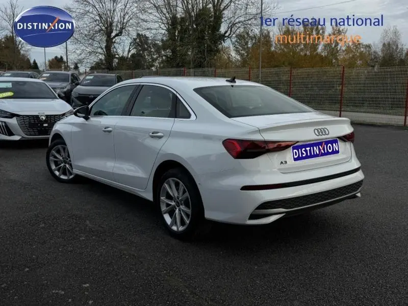 Audi A3 Sportback blanc vue 3/4 arrière droit, avec jantes alu et becquet arrière distinctif.