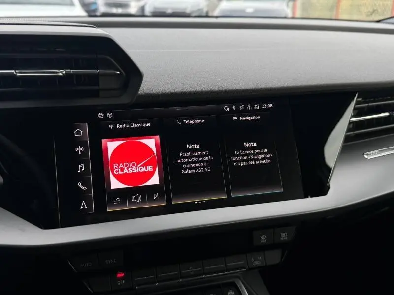 Vue rapprochée de l’écran tactile central noir de l’Audi A3 Sportback 2024 affichant la radio et la navigation.