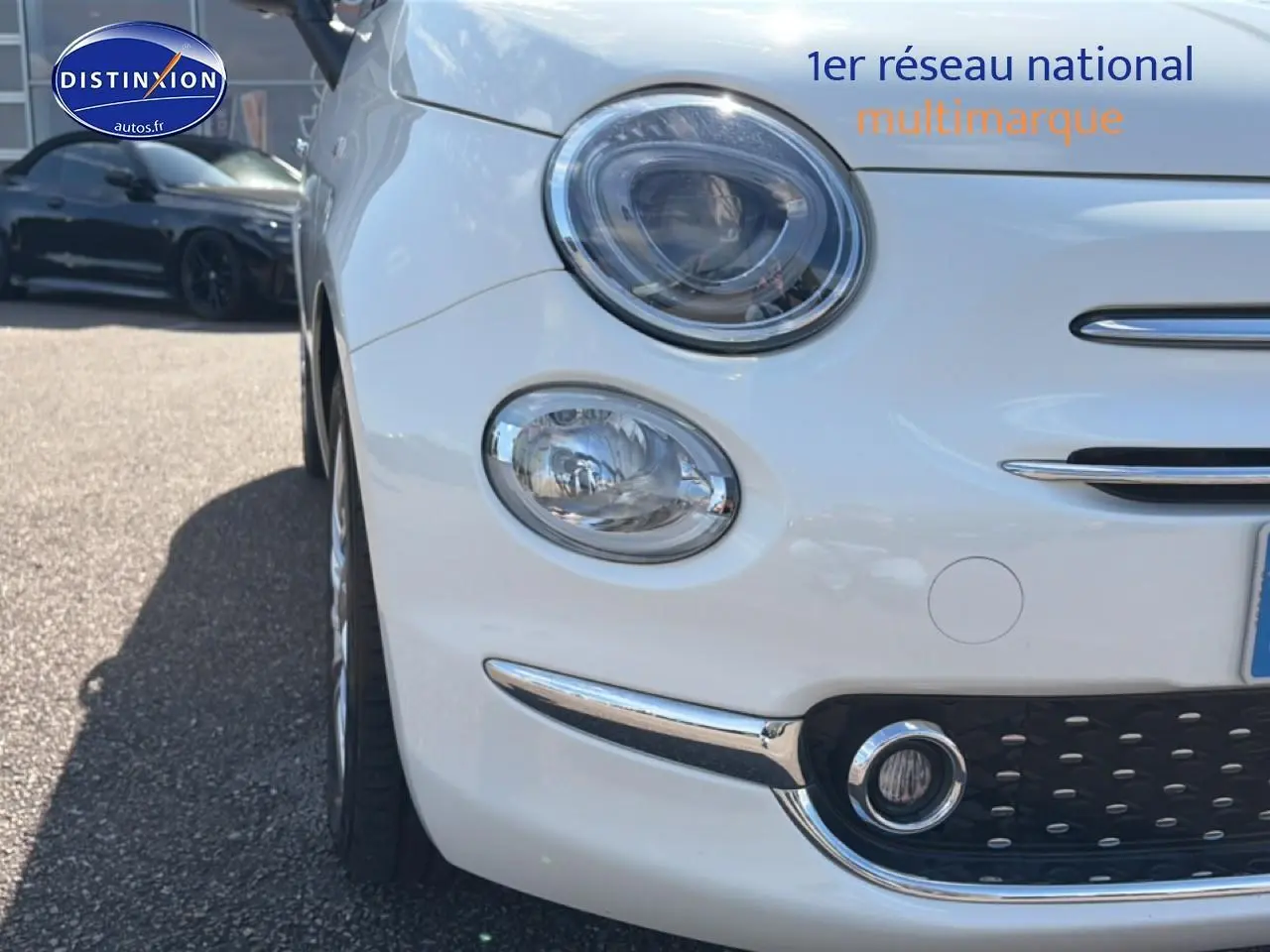 Gros plan sur l'avant gauche d'une Fiat 500 blanche 2023 avec phares ronds et détails chromés.