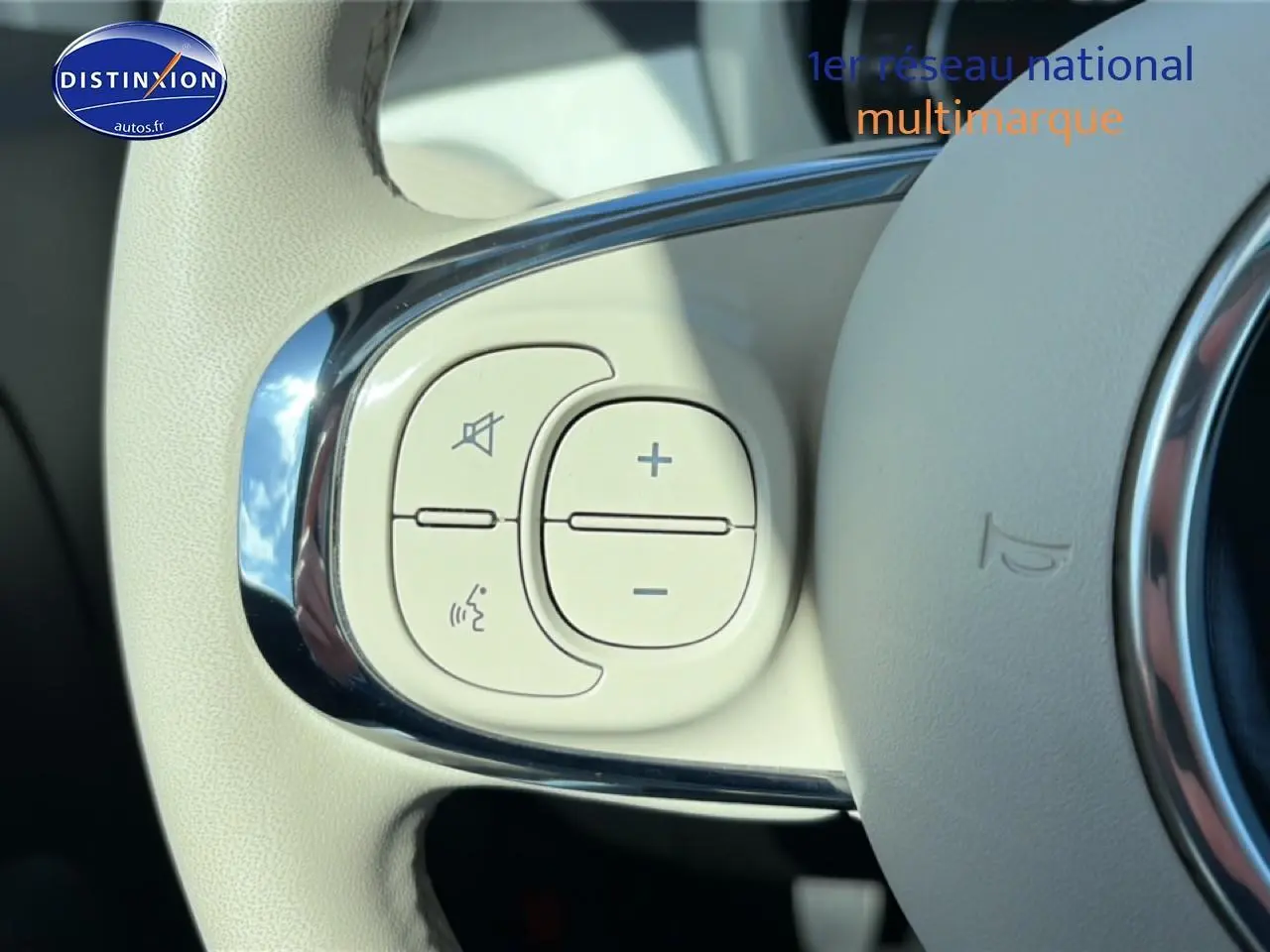 Gros plan sur les commandes audio et vocales blanches intégrées au volant de la FIAT 500 blanche 2023.
