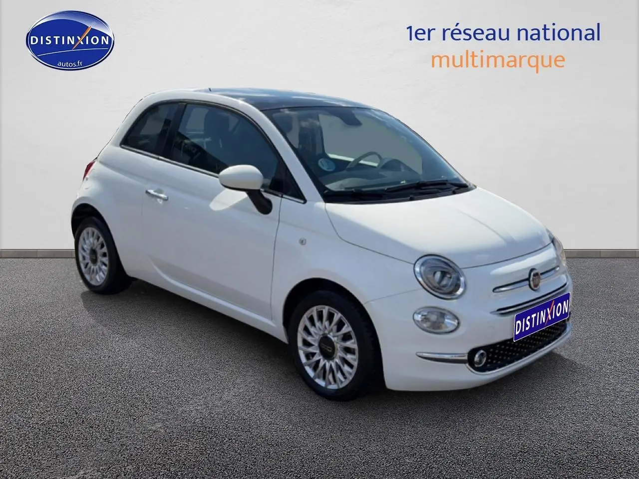 Fiat 500 blanc vue 3/4 avant droit, jantes alu et toit panoramique en verre visibles.