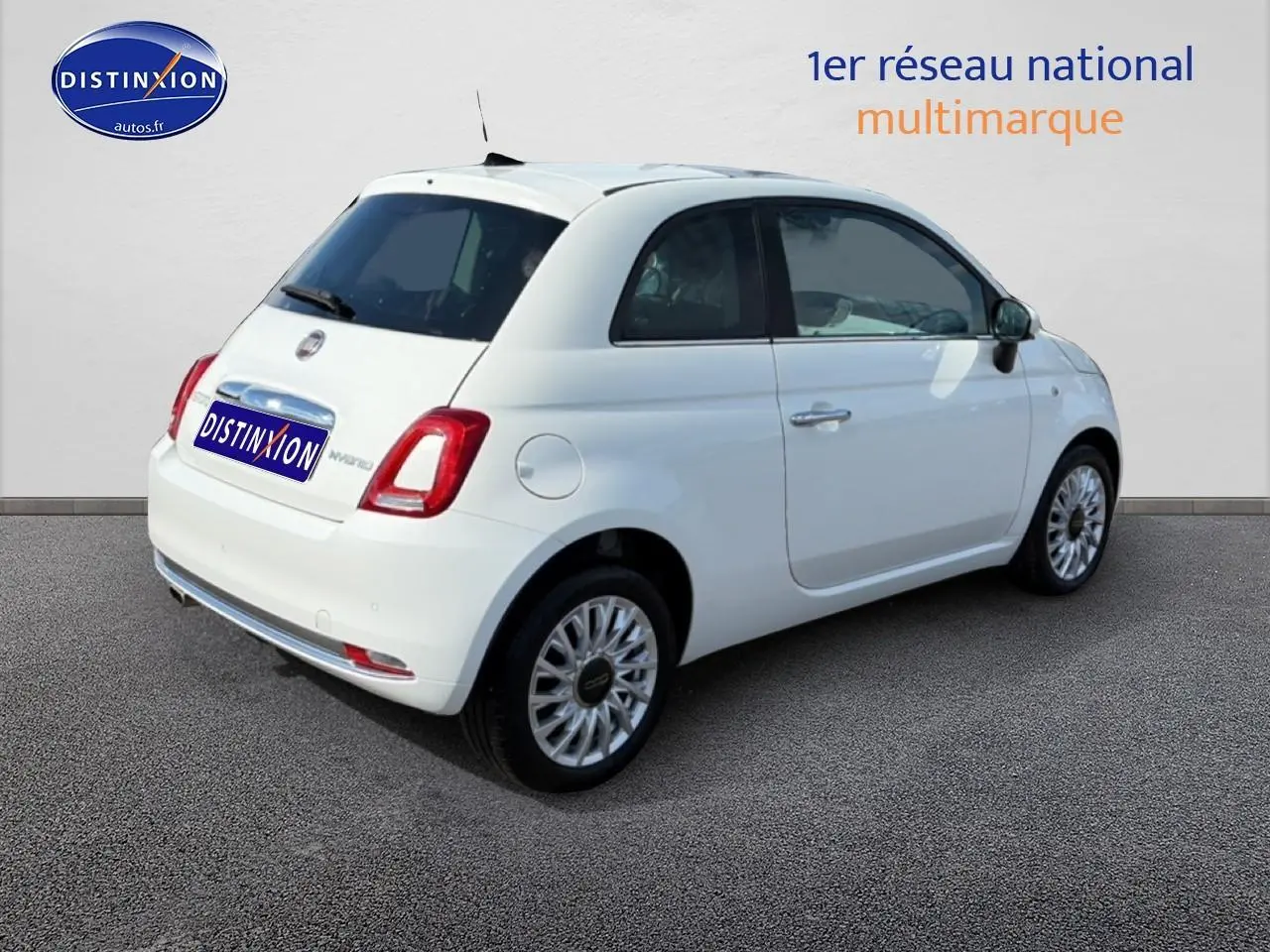 Vue 3/4 arrière droite d'une Fiat 500 blanche 2023 avec jantes alu et toit panoramique en verre.