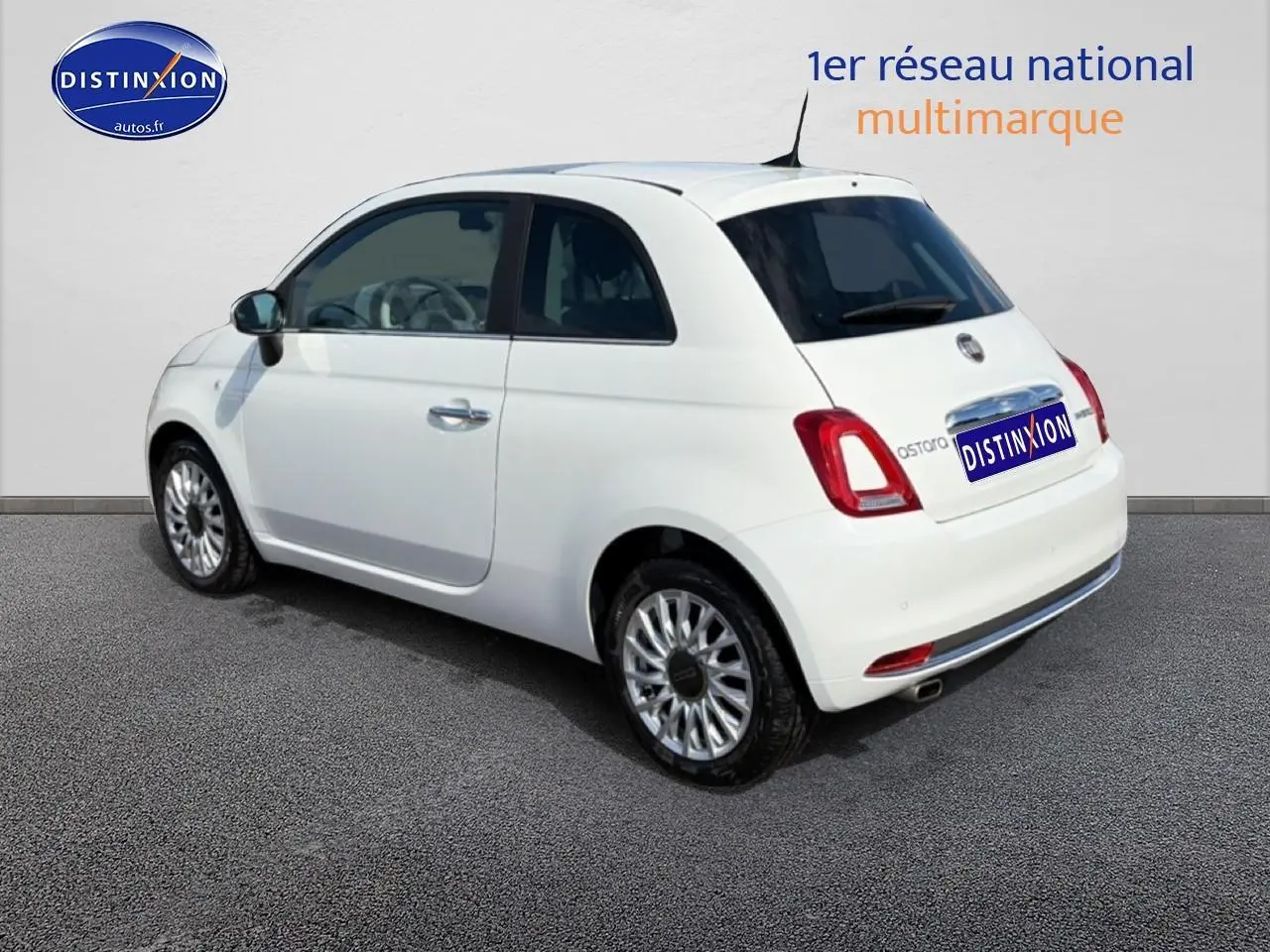 Fiat 500 blanc vue 3/4 arrière droit, jantes alu et vitres teintées sur fond neutre.