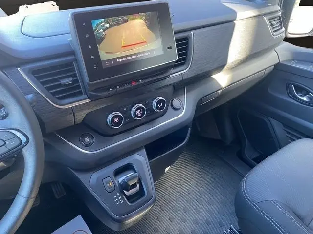 Vue intérieure du tableau de bord du Renault Trafic Fourgon gris foncé, avec écran tactile et commandes de climatisation visibles.