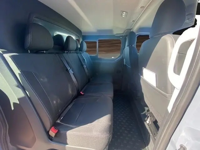 Vue intérieure côté droit sur la banquette arrière noire du Renault Trafic Fourgon gris foncé, avec ceintures de sécurité visibles.