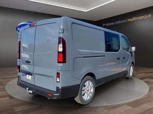 Vue 3/4 arrière droite du Renault Trafic Fourgon gris foncé, avec feux arrière allumés et attelage visible.