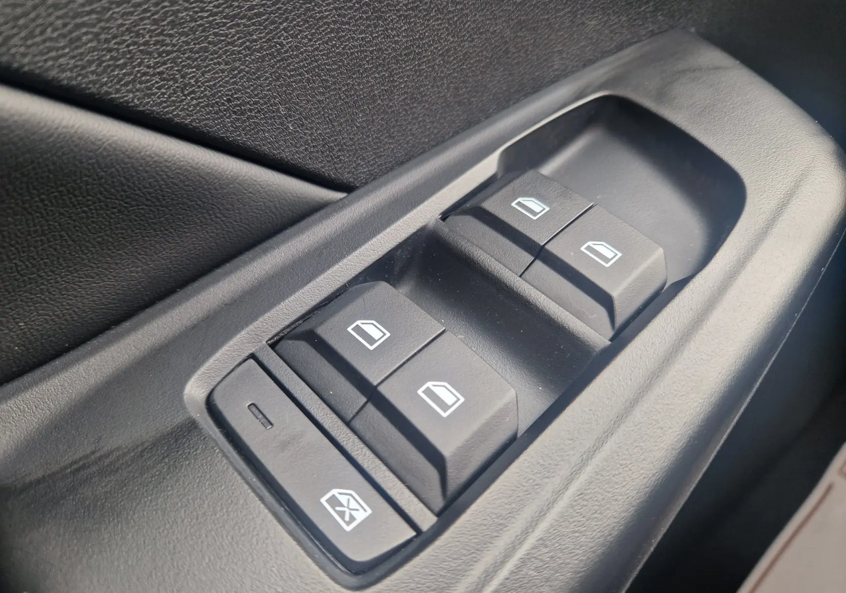Gros plan sur les commandes électriques des vitres côté conducteur de la MG3 1.5L HYBRID+ 195CH LUXURY en intérieur noir.