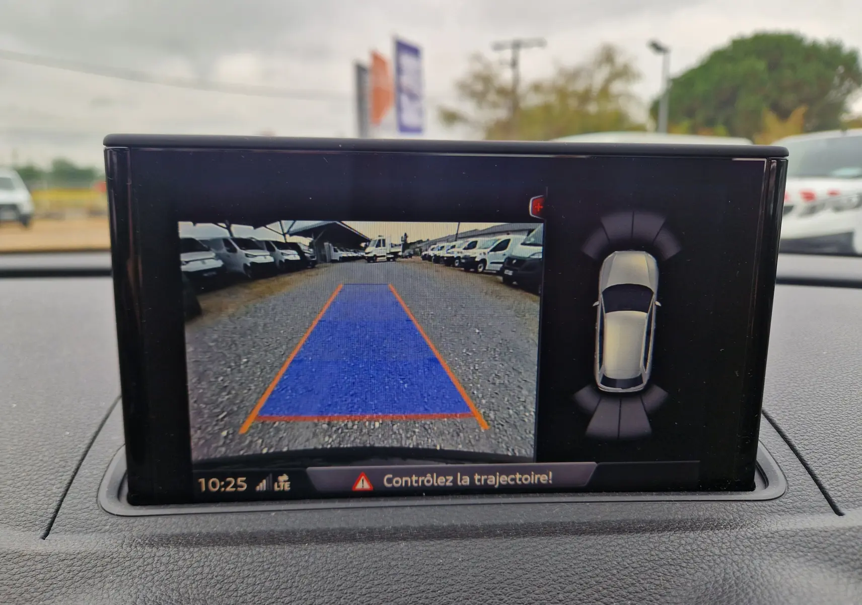 Écran intérieur de l'Audi A3 Sportback noir montrant la caméra de recul avec guidage de trajectoire bleu et orange.