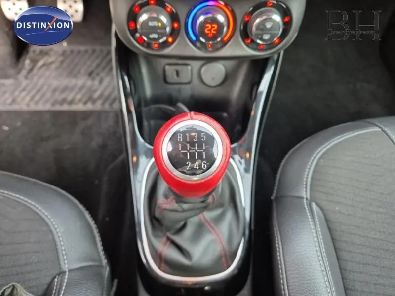 Gros plan sur le levier de vitesses manuel rouge et noir de l'Opel Adam Rocks, avec console centrale et sièges en cuir visibles.