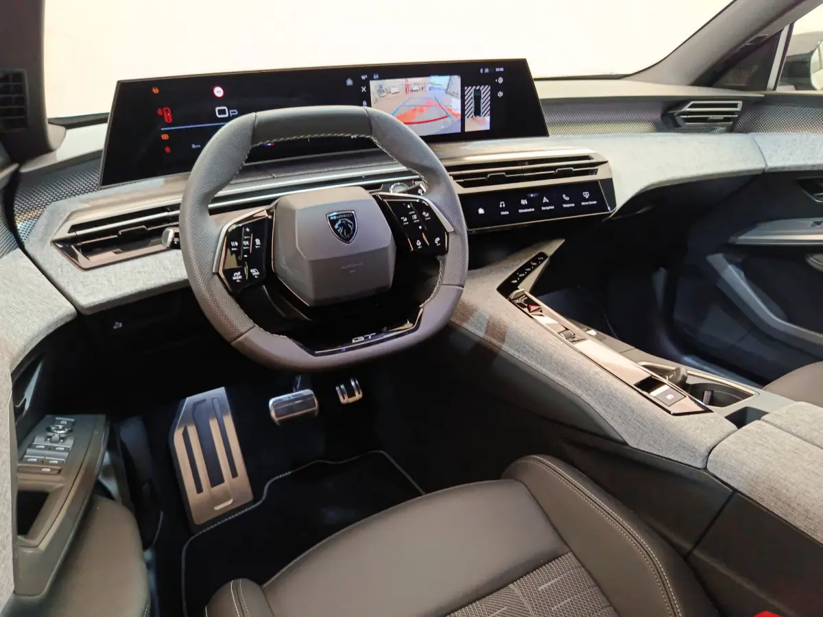 Vue intérieure avant du Peugeot 3008 1.2 Hybrid 145 GT, volant cuir, tableau de bord numérique et console centrale grise.