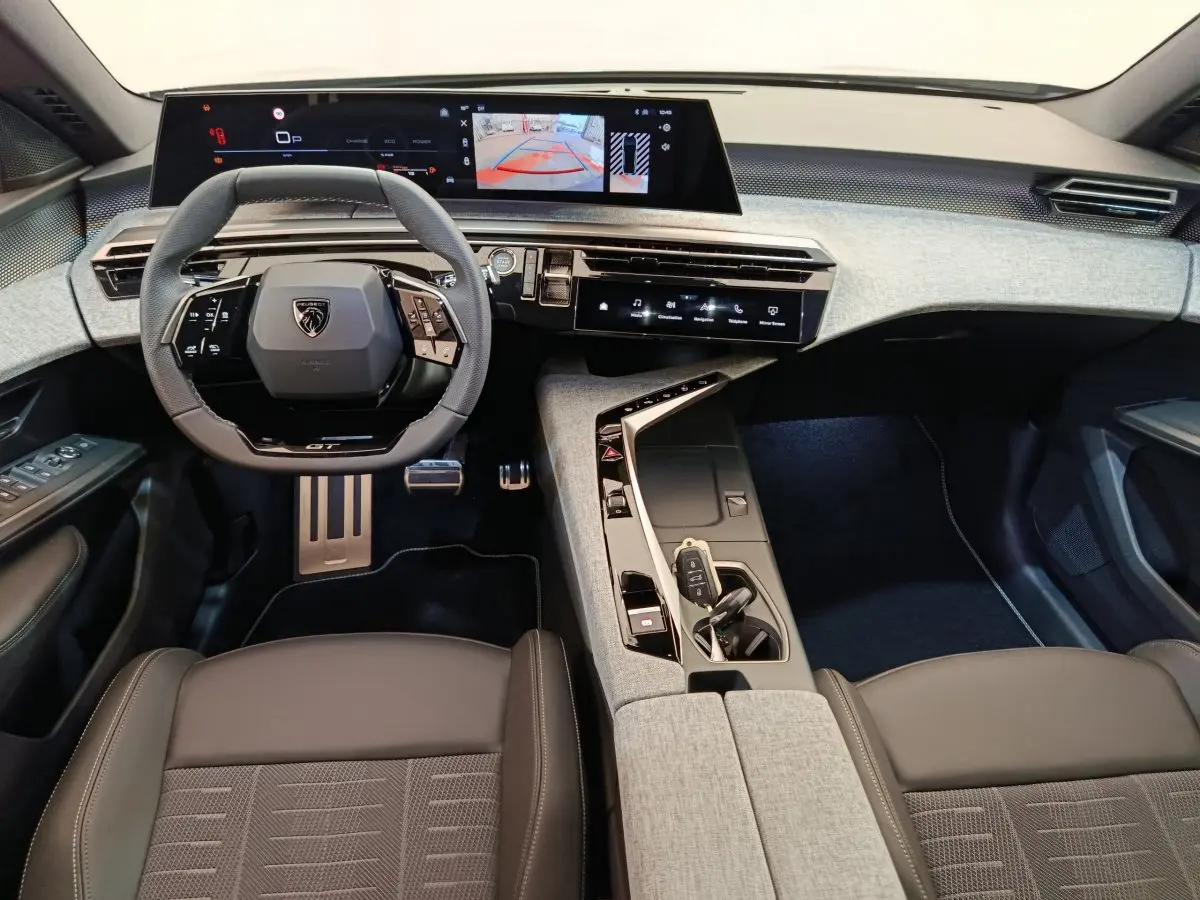Vue intérieure avant du Peugeot 3008 1.2 Hybrid 145 GT, avec volant compact, écran tactile large et finition tissu gris clair.