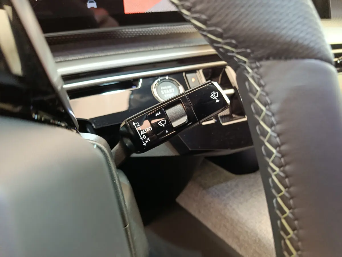 Gros plan sur la commande d’essuie-glace noire et le bouton start/stop dans l’habitacle du Peugeot 3008 noir 2025.